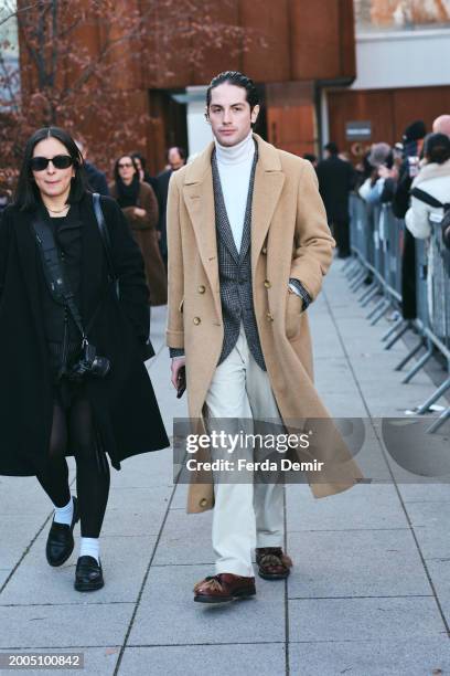 Guest wears camel overcoat cashmere blend overcoat, off white turtleneck sweater, wool herringbone jacket, white trousers, leather fur oafer outside...