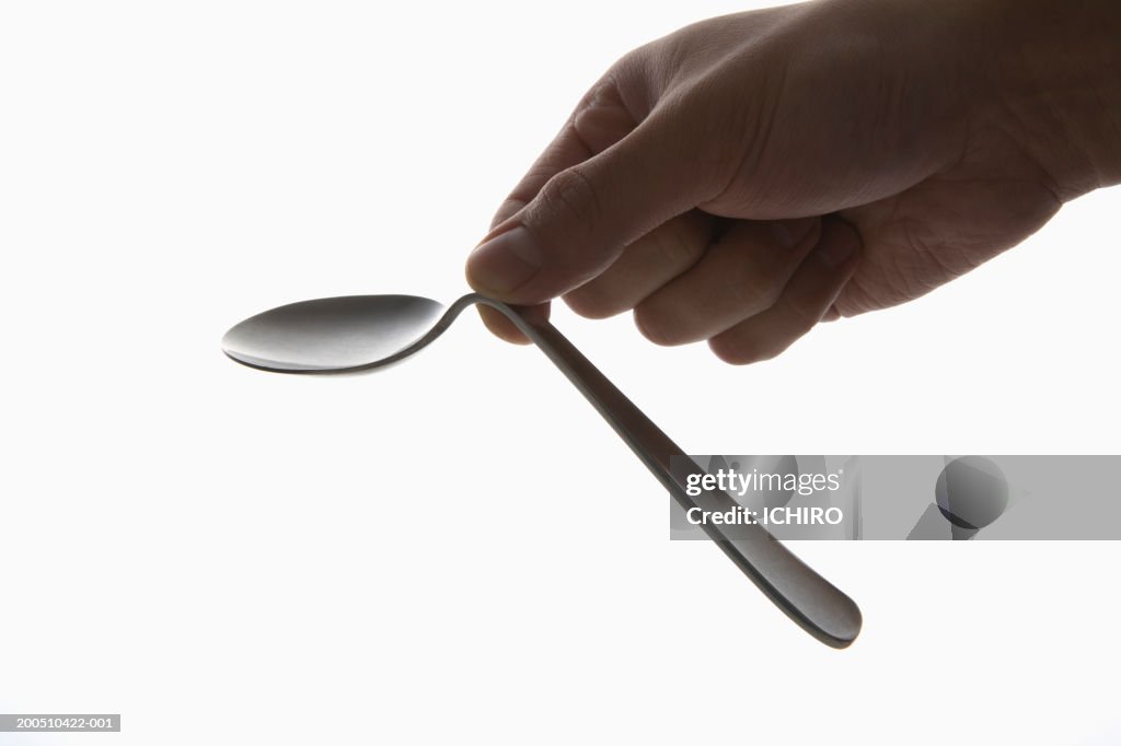 Man bending spoon with fingers, close-up of hand