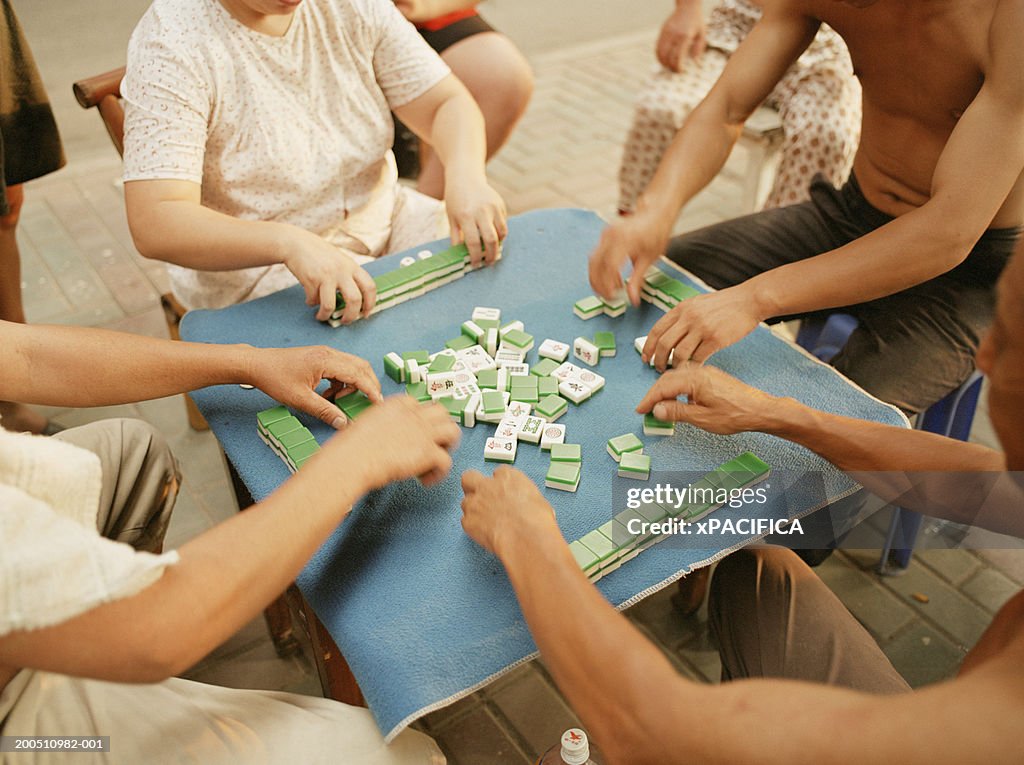 Men and women playing mahjong on street, mid section