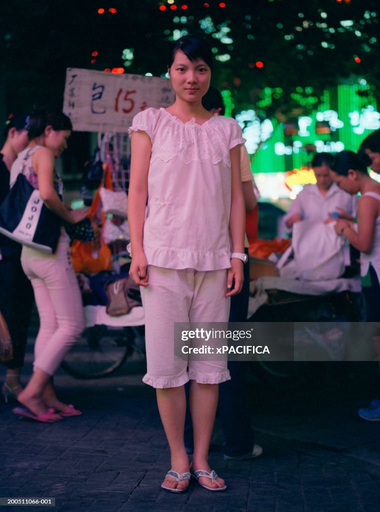 China, Shanghai, teenage girl on street, night, portrait