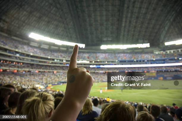 spectator raising finger at baseball game, close-up - baseball stadium photos et images de collection