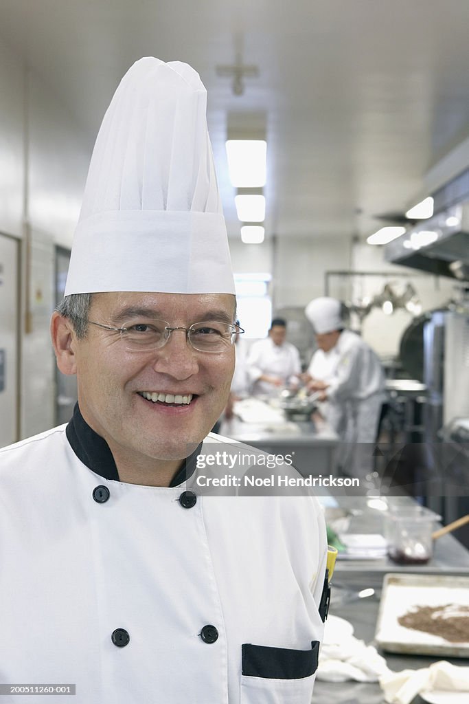 Mature male chef in commercial kitchen, smiling, portrait