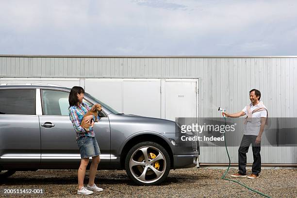 teenage girl (17-19) with dog talking to father washing car on drive - teen wash car stock pictures, royalty-free photos & images