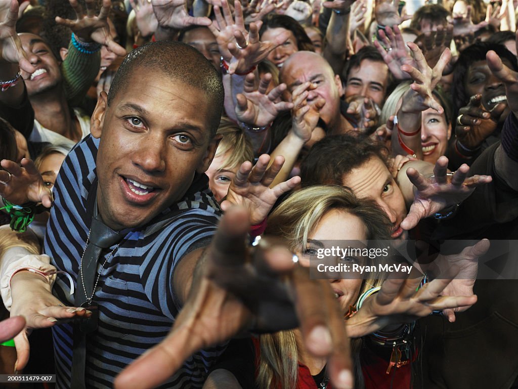 Man in audience at concert reaching hands forward, smiling
