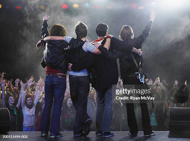band standing before audience on stage with arms around each other - grupo de interpretación musical fotografías e imágenes de stock