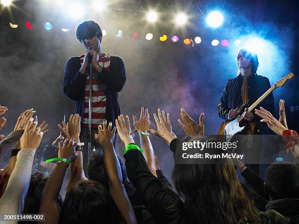 male singer and guitarist performing on stage, audience in foreground - dry ice stage stock pictures, royalty-free photos & images