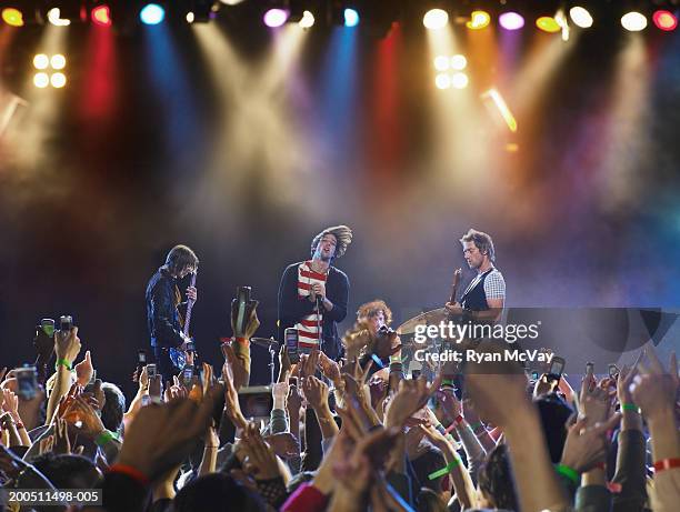 band performing on stage, audience holding up hands in foreground - boy band stockfoto's en -beelden