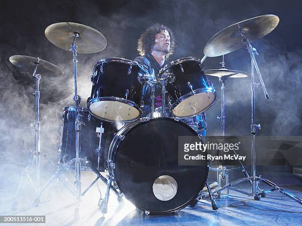 man playing drums on stage surrounded by dry ice - ドラム ストックフォトと画像