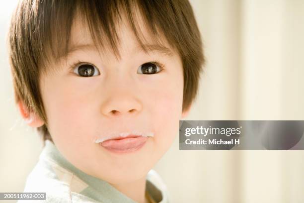 boy (2-4) with milk moustache sticking out tongue, looking up - milk moustache stock-fotos und bilder