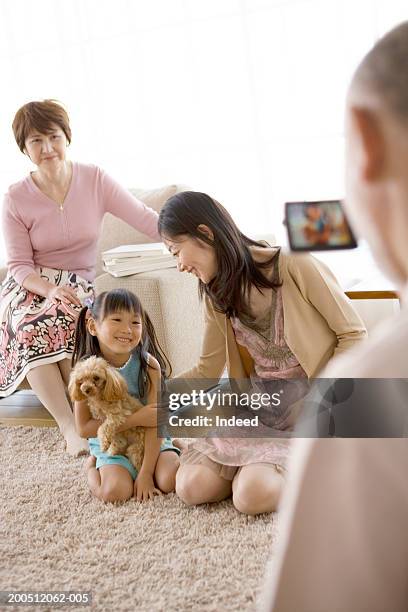 multi-generational family playing with dog at home, smiling - grootmoeder witte achtergrond stockfoto's en -beelden