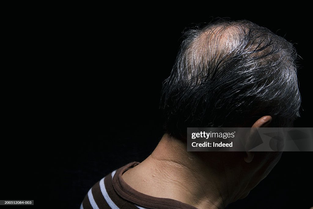 Senior man, against black background, close-up, rear view