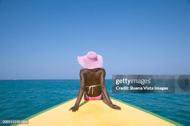 woman sitting on boat's prow, rear view - pink hat stock pictures, royalty-free photos & images