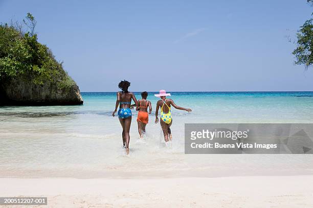 three women running into sea, rear view - jamaica beach bildbanksfoton och bilder