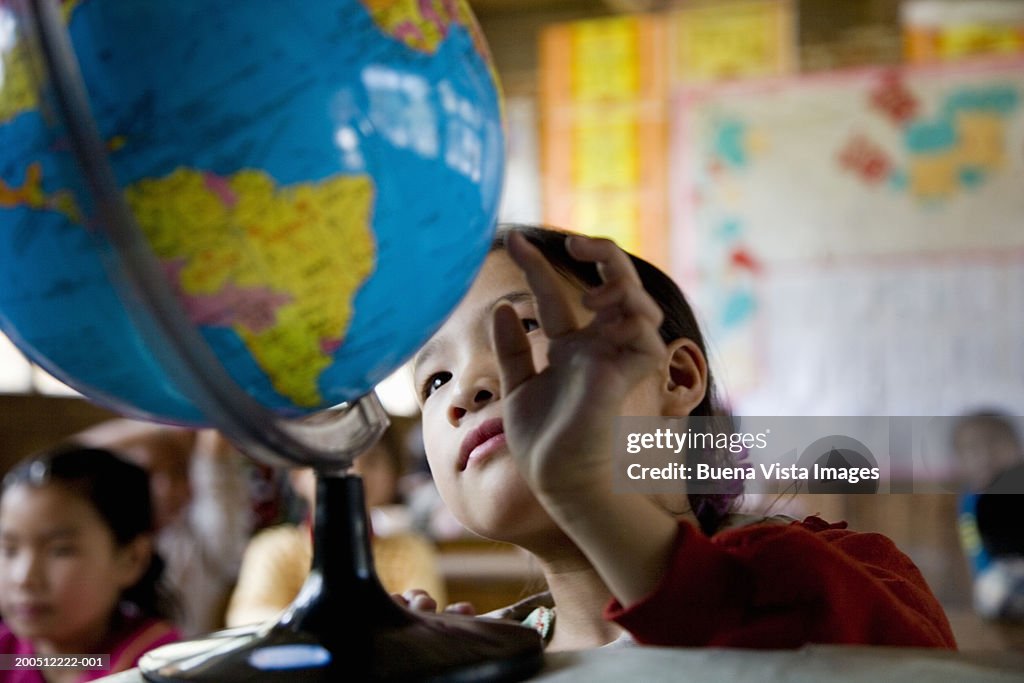 China, Guangxi Province, girl (6-9) looking at globe in class