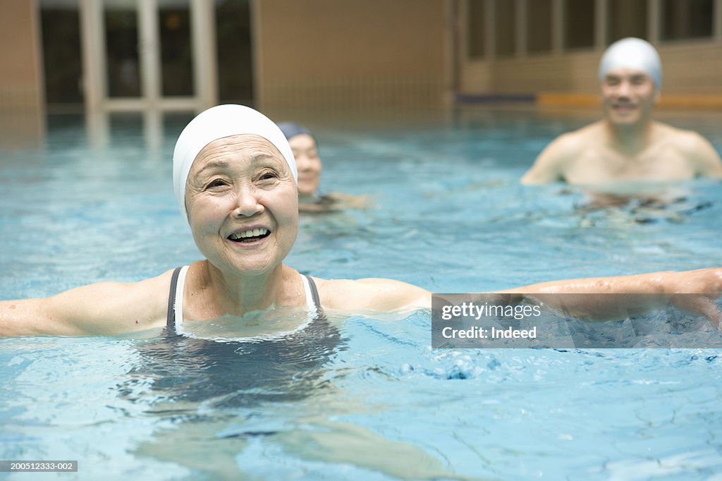 Group of senior adults exercising in swimming pool, smiling