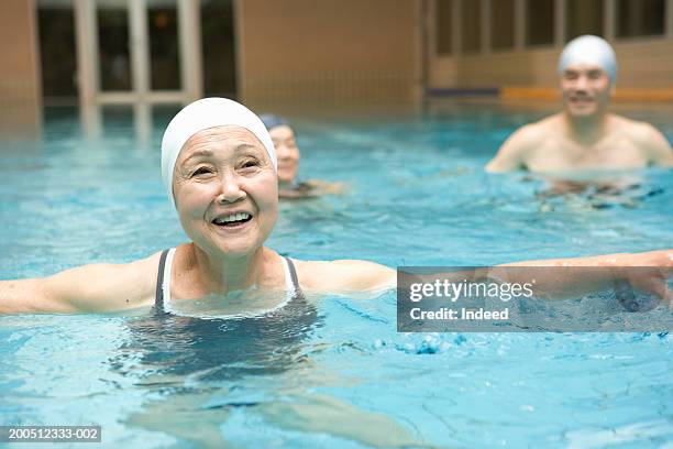 group of senior adults exercising in swimming pool, smiling - japanese old woman stockfoto's en -beelden