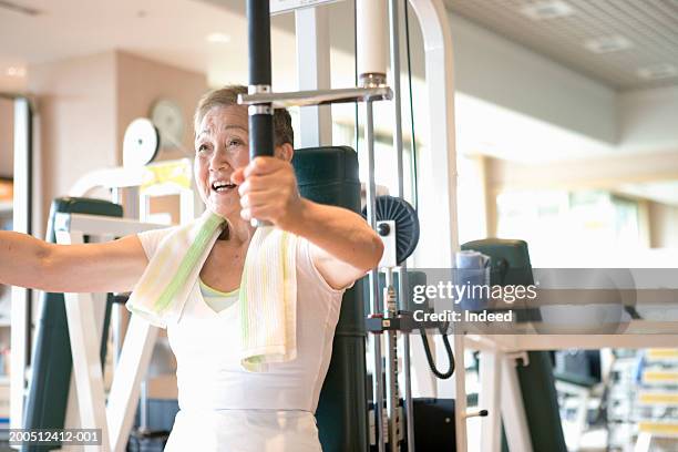 senior woman exercising on machine in gym - entrenamiento de fuerza fotografías e imágenes de stock