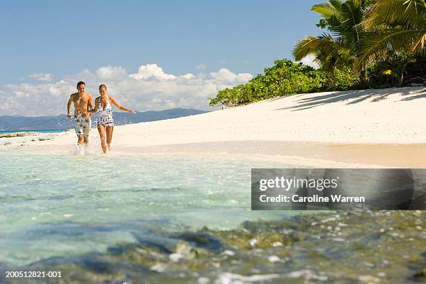 fiji, beqa island, young man and woman running along beach - fiji people stock pictures, royalty-free photos & images