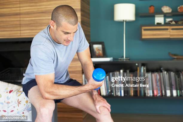 man performing arm curls with dumbell at home - musculation des biceps photos et images de collection