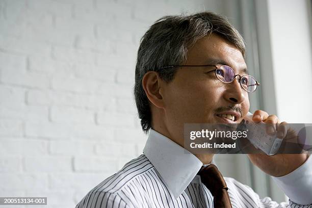 mature businessman using cordless telephone, smiling, close-up - 40代 男性 ストックフォトと画像