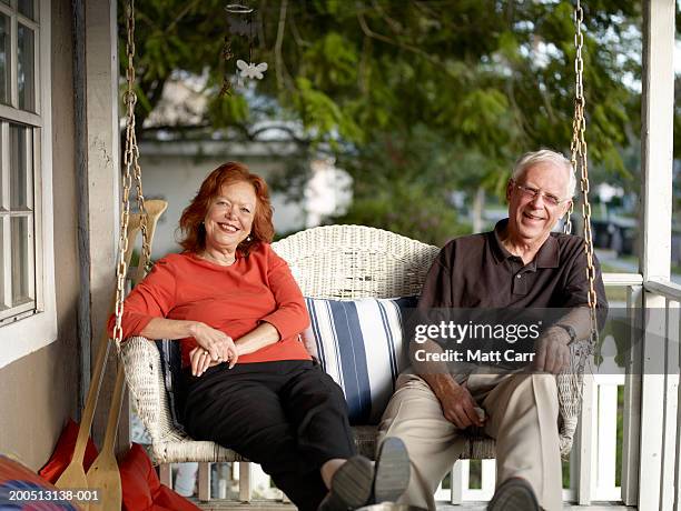 senior couple sitting on porch swing, smiling, portrait - swing chair stock pictures, royalty-free photos & images