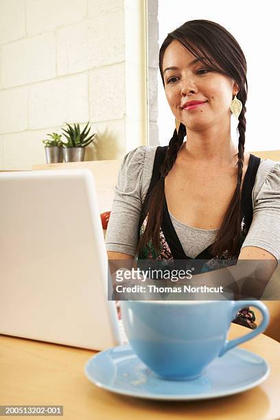 young woman with coffee using laptop in cafe, smiling - native korean stock pictures, royalty-free photos & images
