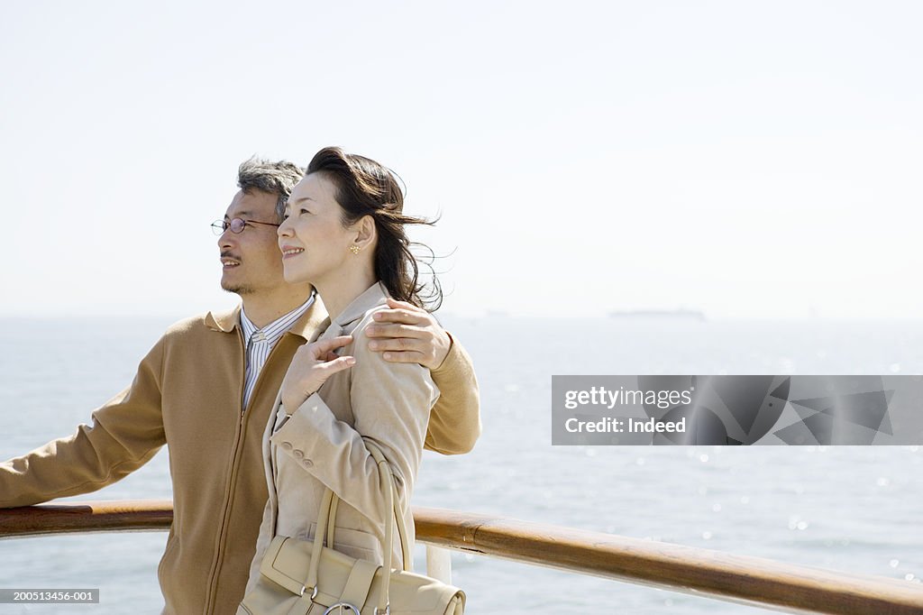 Mature couple embracing on deck of cruise ship, smiling, side view