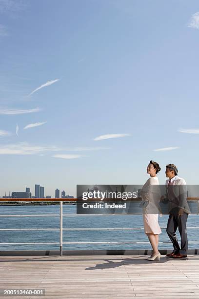 mature couple on deck of cruise ship, skyline in background, side view - boat deck background stock pictures, royalty-free photos & images