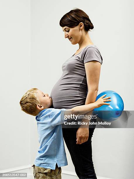 pregnant mother smiling down at son (2-4) holding balloon - sandy molloy stock pictures, royalty-free photos & images