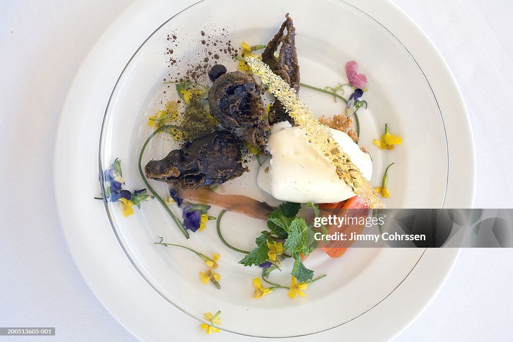Desert on plate garnished with flowers, close-up