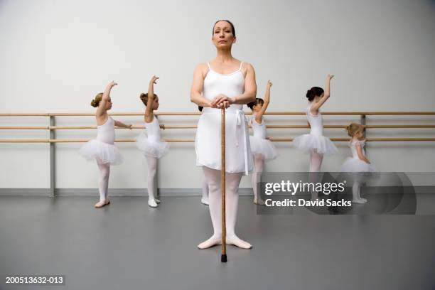 ballet teacher holding stick, children (3-12) practising in background - preciseness stock pictures, royalty-free photos & images