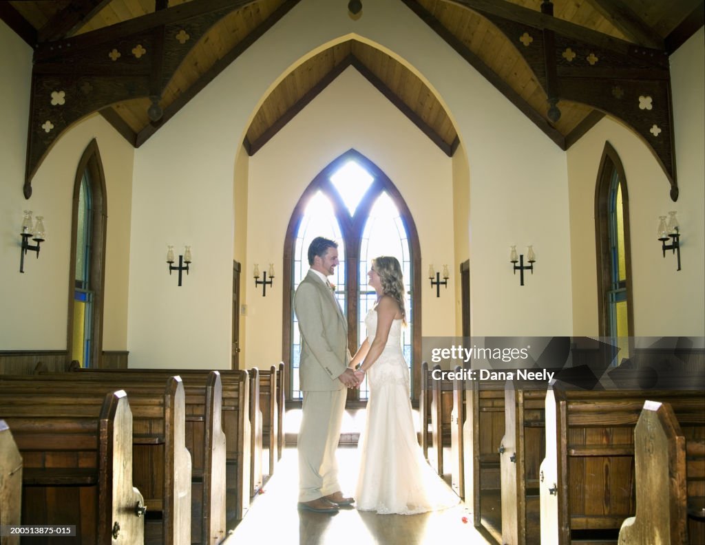Bride and groom holding hands in chapel, side view