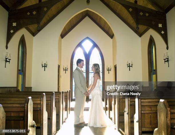 bride and groom holding hands in chapel, side view - wedding ceremony aisle stock pictures, royalty-free photos & images