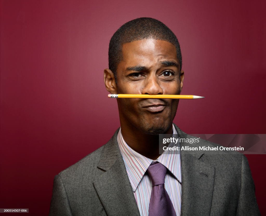 Businessman balancing pencil on nose, portrait