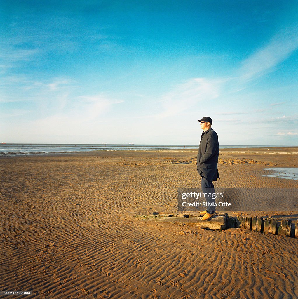 Man standing on mudflats, side view