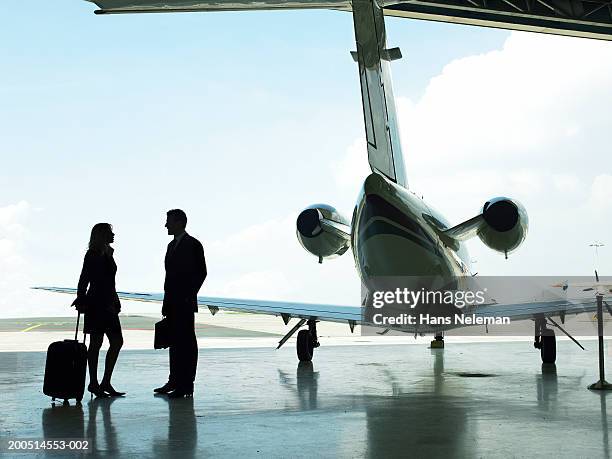 business people standing by private plane in hangar, silhouette - private jet stockfoto's en -beelden