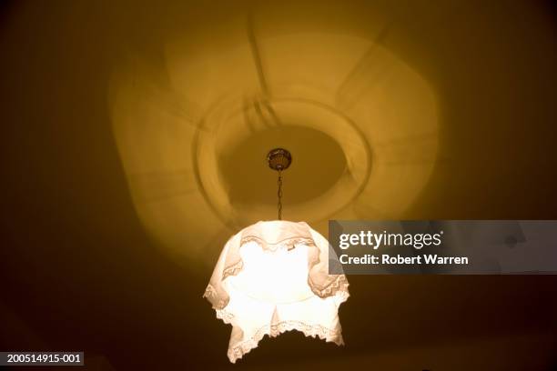 lampshade on illuminated ceiling bulb, low angle view - fitting stockfoto's en -beelden