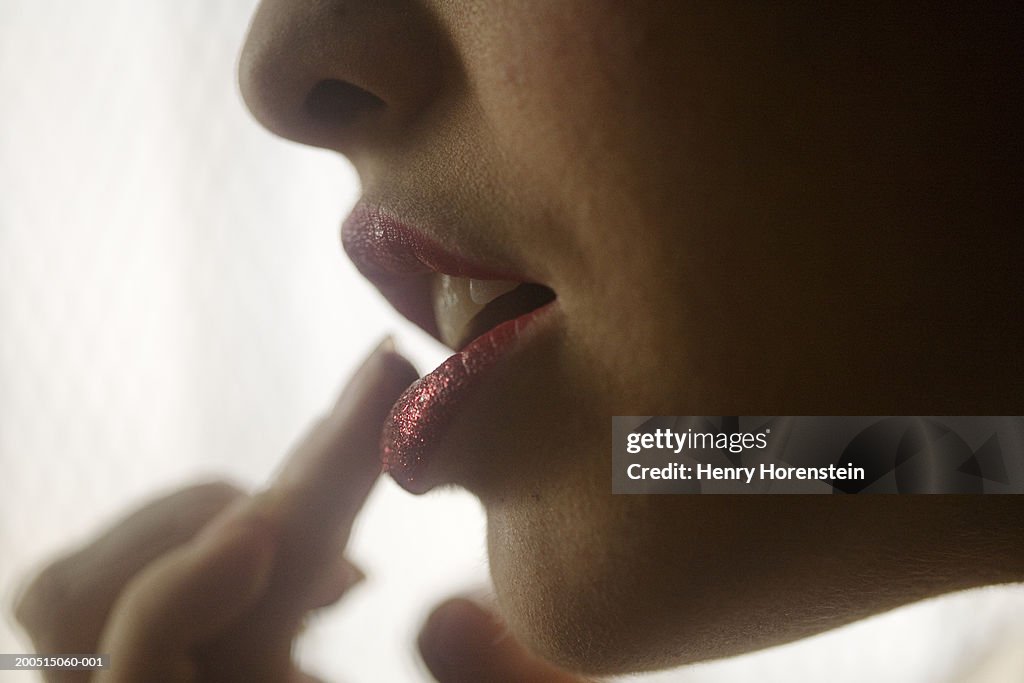 Woman putting on lipstick, close-up of mouth, side view