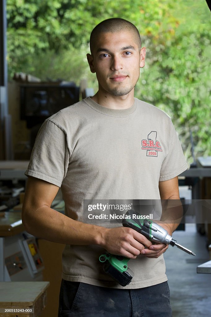 Portrait, young man holding  electric drill.