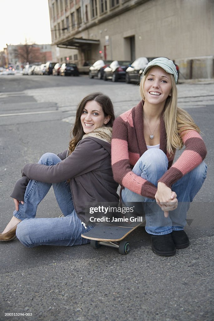 Young women sitting on skateboard, portrait