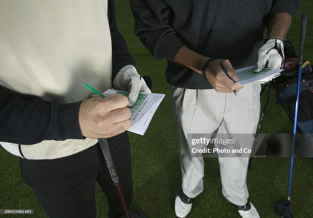 Two men making notes on golf score cards