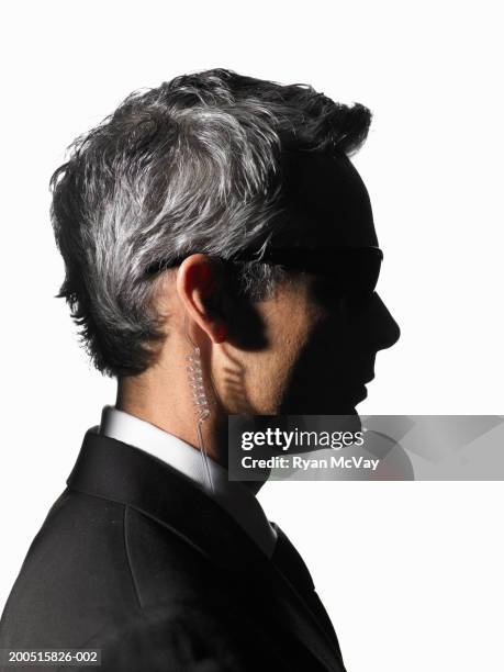 mature male secret service agent wearing hands-free device, side view - secret service agent stock pictures, royalty-free photos & images