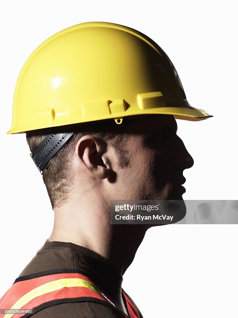 Young male construction worker wearing hardhat, side view