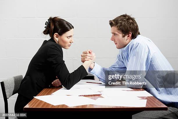 business woman and business man arm wrestling over table, side view - face off fotografías e imágenes de stock