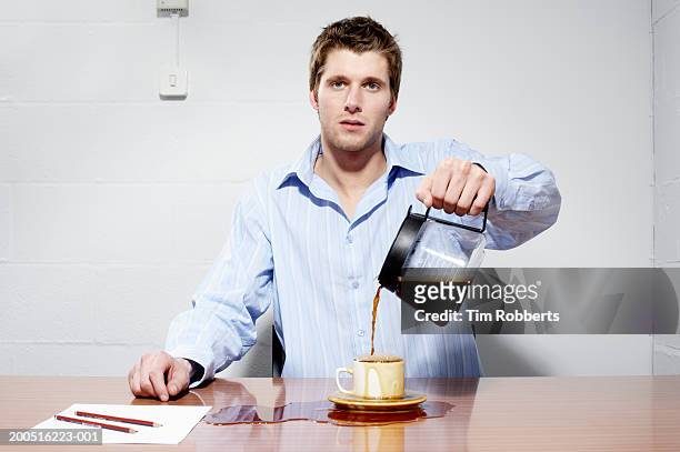 business man pouring coffee into cup and onto table - cup portraits foto e immagini stock