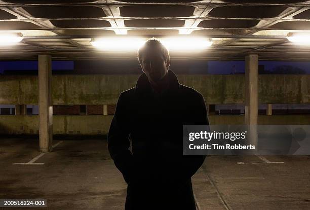 man standing in carpark in shadow at night, upper half - gângster - fotografias e filmes do acervo