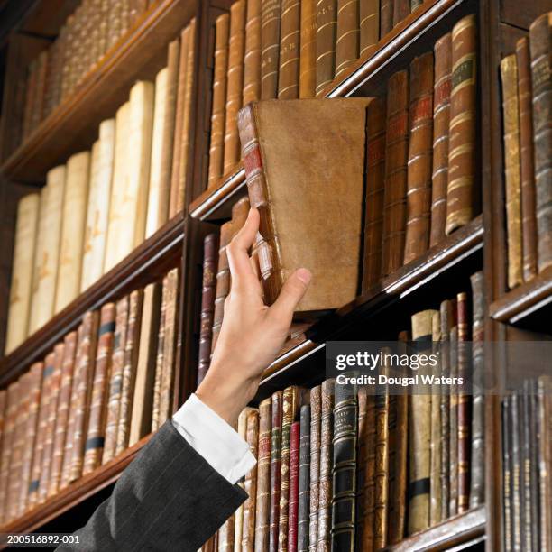 woman reaching for book in library - law books fotografías e imágenes de stock