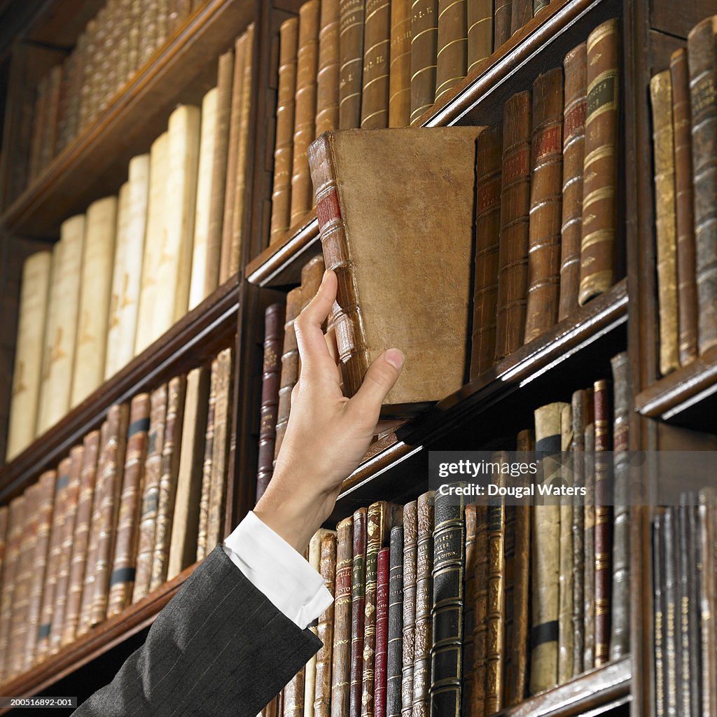 Woman reaching for book in library