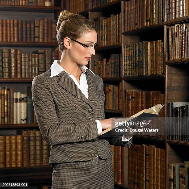young woman reading book in library - hardbound stock pictures, royalty-free photos & images