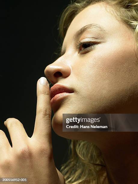 young woman putting finger to lips, close-up, profile - woman with finger on lips stock pictures, royalty-free photos & images
